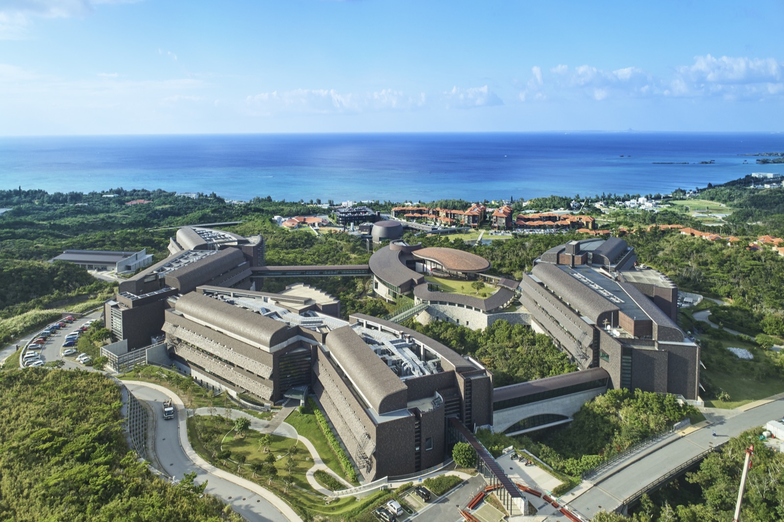 Aerial view of the OIST campus buildings overlooking the ocean.