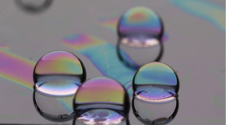 Iridescent oil droplets oleoplaning across a lubricated surface.